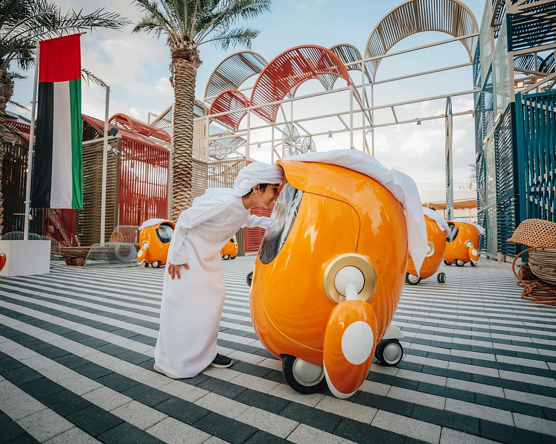 boy in arabic clothing looking at a robot